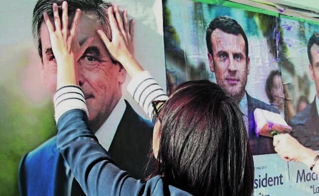 Supporters of François Fillon cover posters of Emmanuel Macron prior to the first electoral round for the French presidency 2017- Photo: Bob Edme/AP