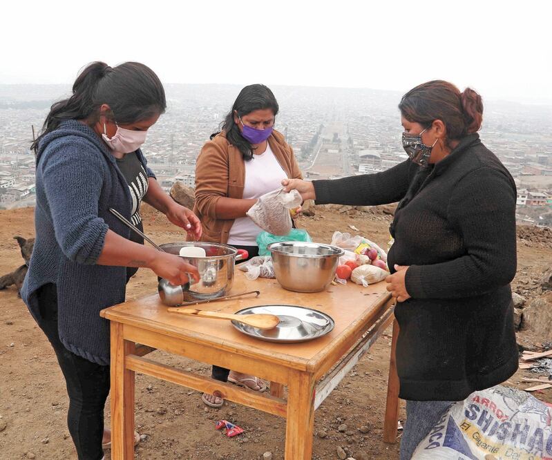 Peruanas preparan comida para familias de escasos recursos en Lima. Laviolencia física contra ellas es un grave problema en el país. MARTÍN MEJÍA. AP 