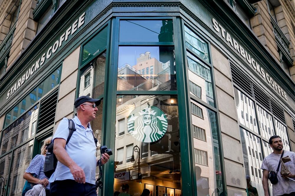 Peatones pasan frente a un Starbucks en Manhattan, Nueva York. La empresa rechaza las acusaciones del sindicato de que está prohibiendo decoraciones alusivas al mes LGBTQ. Foto: AP