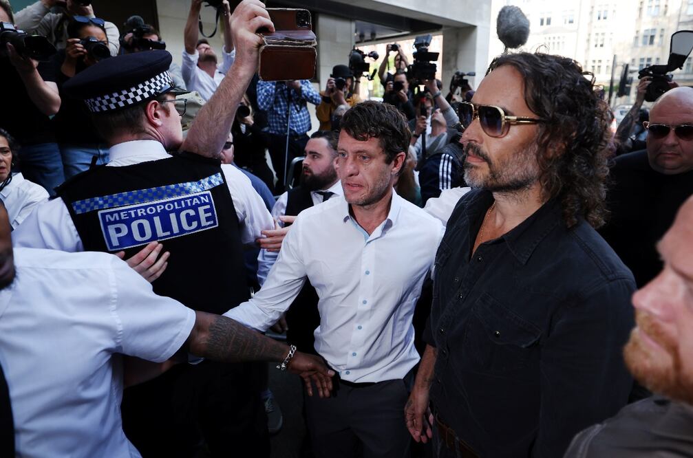 Policía rodea al actor y comediante Russell Brand a su llegada a la audiencia en Londres. Foto: EFE.