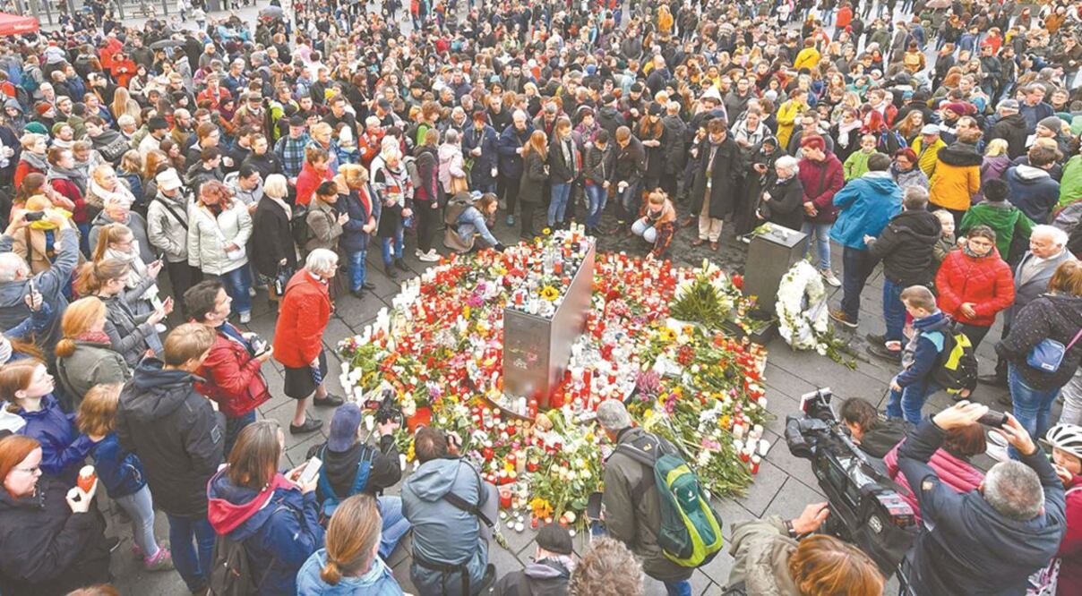 Alrededor de un monumento conmemorativo de flores y velas en la plaza del mercado en Halle, las personas recuerdan a las víctimas del ataque. HENDRIK SCHMIDT. AFP