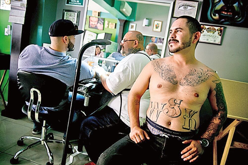 Tras ser deportado de Estados Unidos en 2010, Spanky (el tatuador al fondo) abrió un establecimiento de tatuajes en Tijuana, llamado “No Mercy”, lo que significa “sin piedad” en español (Foto: ROBERTO ARMOCIDA)