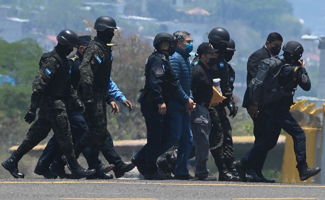 El expresidente de Honduras, Juan Orlando Hernández, es escoltado por agentes de policía a su llegada a una base de la Fuerza Aérea en Tegucigalpa. Foto: AFP