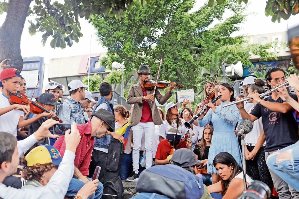 El violinista venezolano Wuilly Arteaga (al centro) y varios músicos ofrecieron ayer un concierto gratuito durante una reunión en protesta contra el gobierno del presidente Nicolás Maduro (MARCO BELLO. REUTERS)