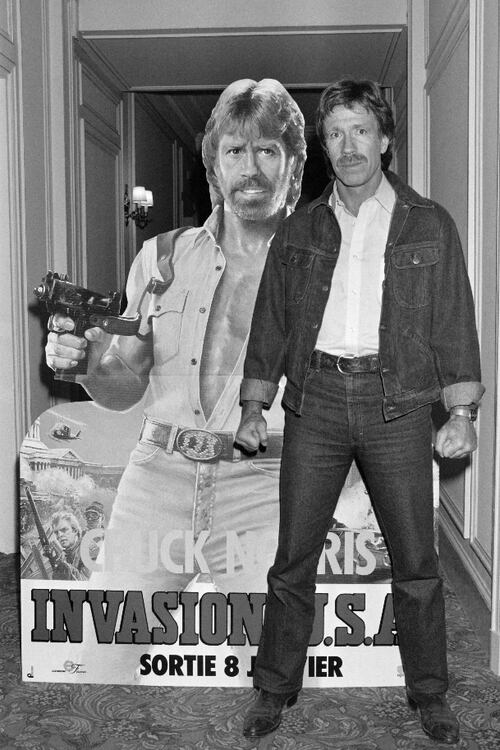 El actor estadounidense Chuck Norris posa el 27 de noviembre de 1985 frente al cartel de la película 