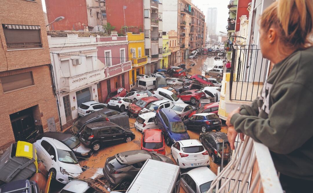Una mujer mira desde su balcón los vehículos atrapados en la calle luego de la inundación en Valencia. Foto: de Alberto Saiz. AP