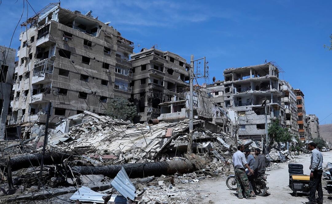 Gente de pie ante los edificios dañados en la localidad de Duma, donde se sospecha hubo un ataque con armas químicas cerca de Damasco, Siria, el 16 de abril de 2018. Foto: AP