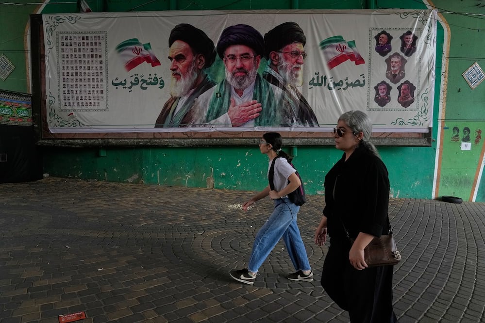 Iraníes pasan junto a una pancarta con los retratos de los fallecidos ayatolas Khomeini y Ali Jamenei (izq. y der.), y el actual líder supremo, Mojtaba Jamenei, en Teherán. FOTO: VAHID SALEMI. AP