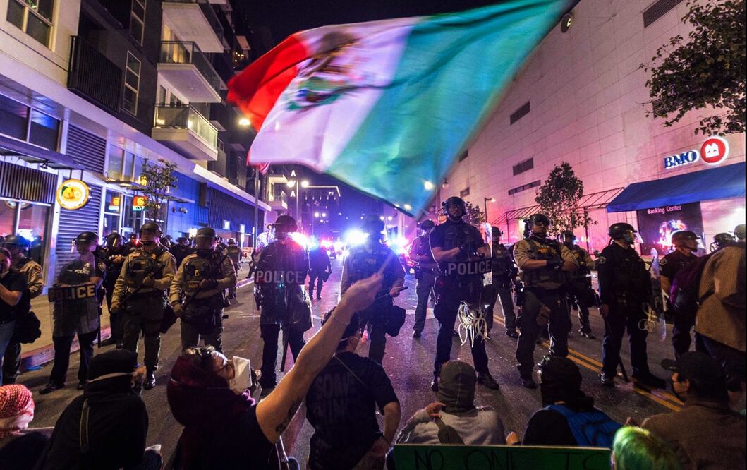 Manifestantes ondeando una bandera de México frente a policías antidisturbios durante una manifestación tras los operativos federales de inmigración en Los Ángeles, California, el 9 de junio de 2025. Foto: AFP