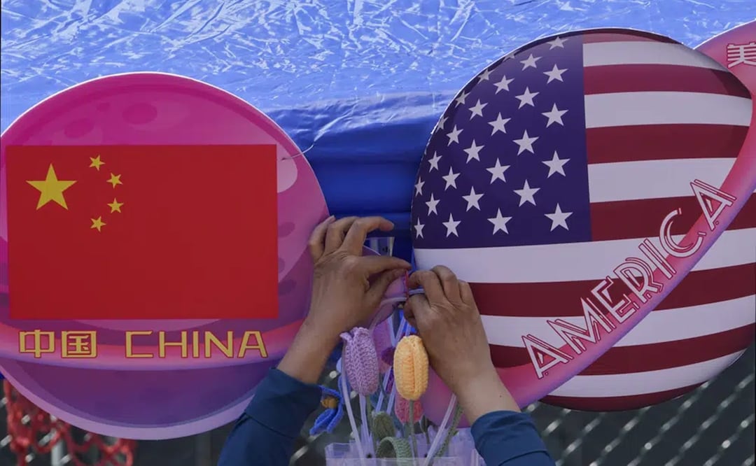 Un comerciante ata unas flores entre dos banderas de China y EU con forma de planeta, durante el Carnaval de Primavera en Beijing. Foto: AP