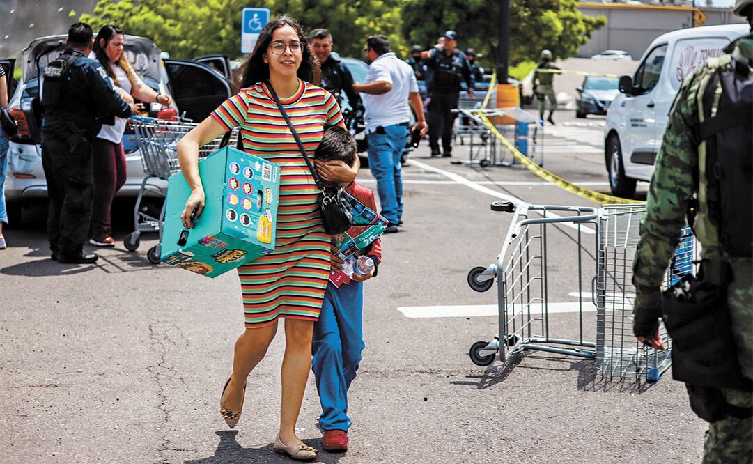 Una mujer le cubre los ojos a su hijo para que no vea el cadáver de un hombre asesinado a balazos en el estacionamiento de un supermercado en el sur de Culiacán. Foto: Iván Medina | 24 MM
