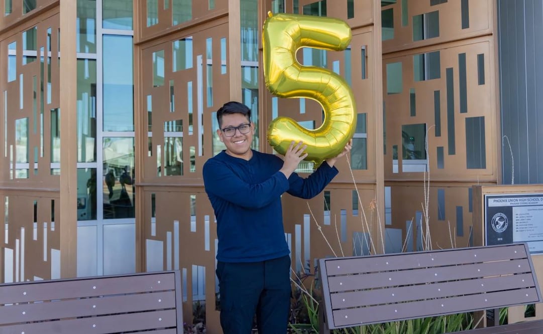 Fotografía divulgada por el Distrito de Escuelas Secundarias Phoenix Union donde aparece Joseph Parra Miguel, de 18 años e hijo de inmigrantes mexicanos, sosteniendo un globo en forma del número cinco en alusión a su logro de 5 millones de dólares en becas. Foto: EFE