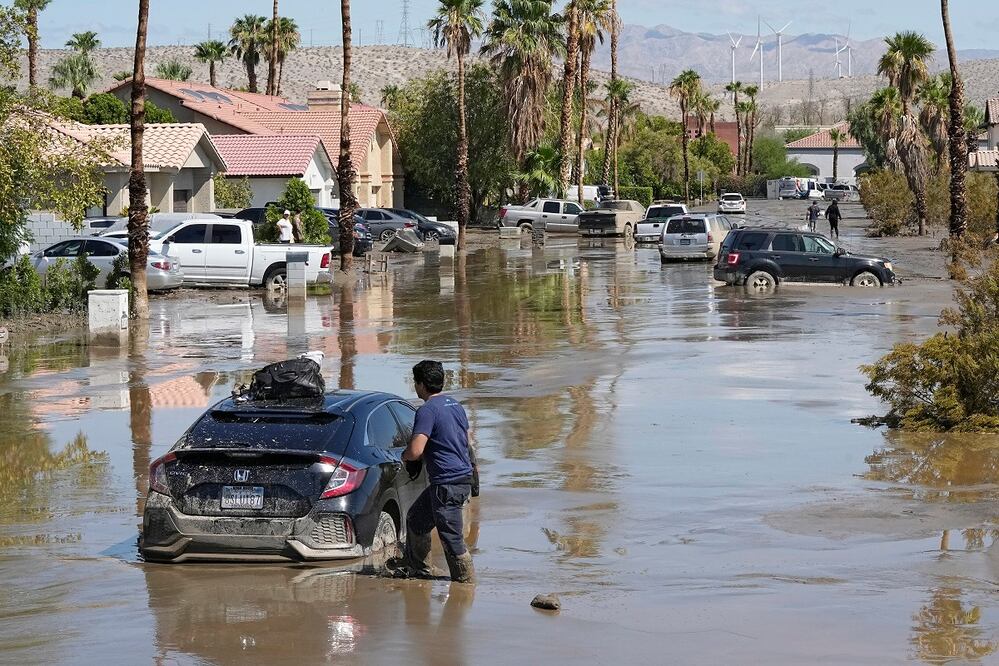 Dorian Padilla espera la llegada de una grúa, después de que su auto quedó atascado en el lodo, tras el paso de Hilary, en Cathedral City, California. Foto: AP