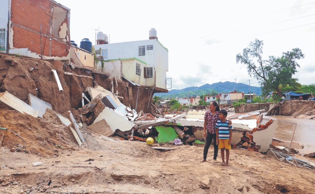 Juana Mendoza y su hijo ven cómo la crecida del río, causada por las lluvias del huracán John, se llevó lo que fue su casa durante más de un año y su refugio tras huir de una problemática de violencia doméstica, en la Costa Chica de Guerrero. Ahora busca empezar de nuevo en otra vivienda. Fotos: Valente Rosas. El Universal