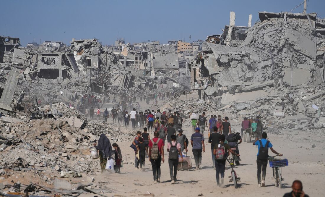 Palestinos desplazados caminan junto a edificios destruidos mientras regresan a sus hogares en el barrio de Zeitoun, en la ciudad de Gaza. Foto: AP