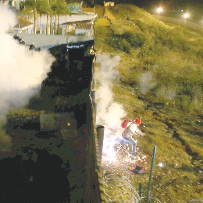 Un migrante centroamericano corre después de haber cruzado la valla fronteriza desde Tijuana, mientras agentes migratorios de EU lo observan. MOHAMMED SALEM. REUTERS