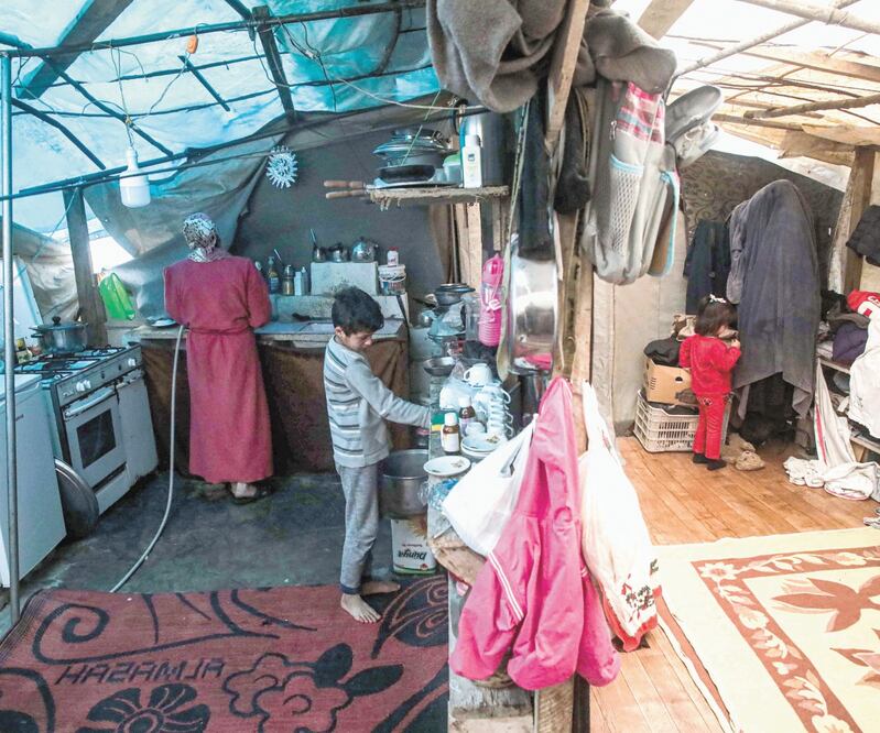 Miembros de una familia siria desplazada, dentro de su tienda en un campamento en Khirbet al-Joz, en Idlib, donde los residentes apenas tienen suficiente dinero para comprar comida y ropa para mantenerse calientes. Foto: AAREF WATAD. AFP