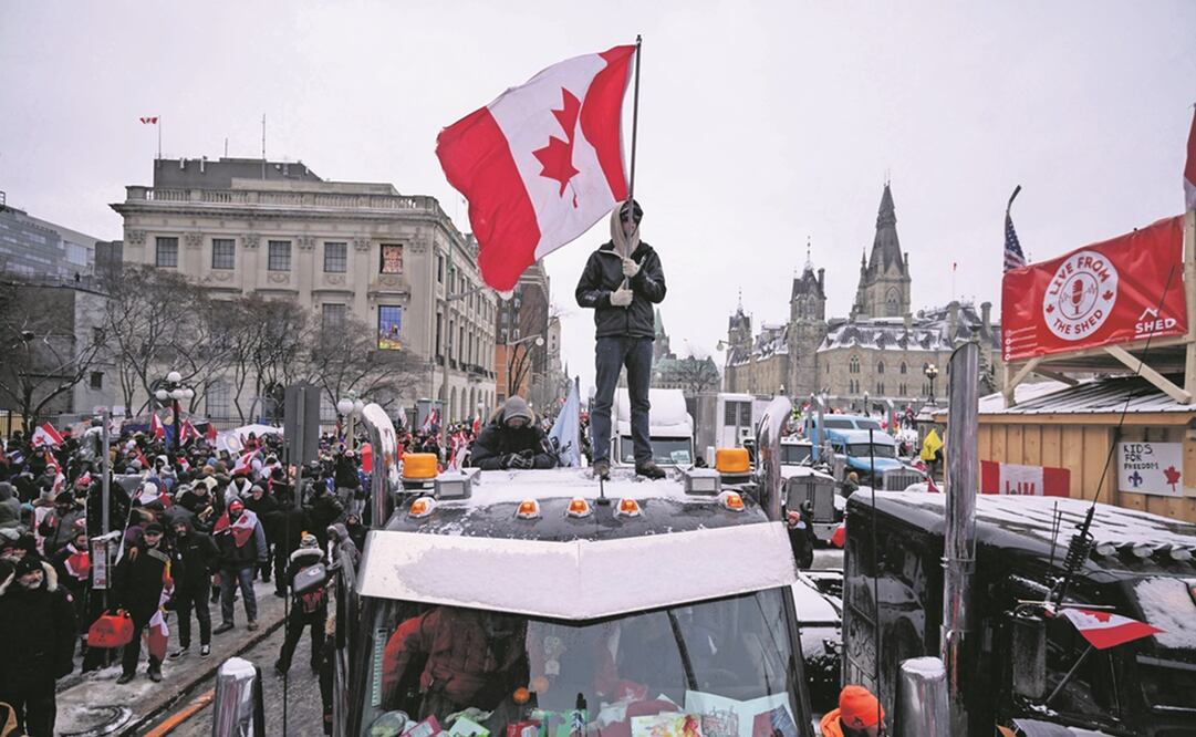 Un manifestante encuma de un camión, con la bandera canadiense, durante una de las protestas afuera del Parlamento, en Ottawa. Foto: ED JONES/ AFP