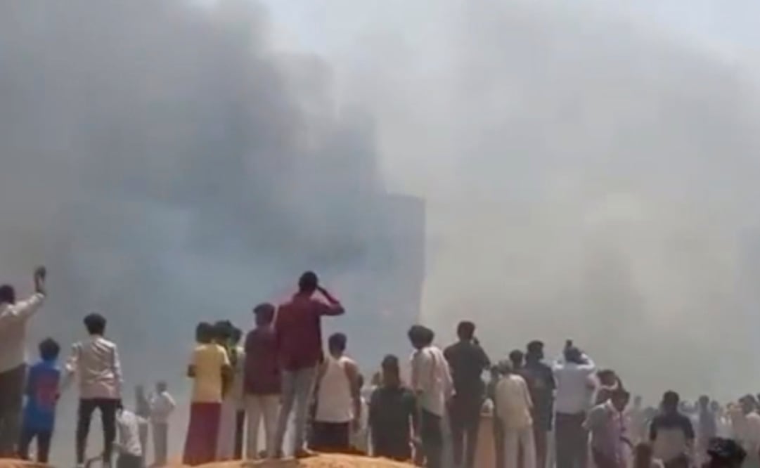 Gente mira una humareda después de que un avión se estrellara en Ahmedabad, en el estado de Gujarat, India, el jueves 12 de junio de 2025. Foto: de Mohan Nakum via AP