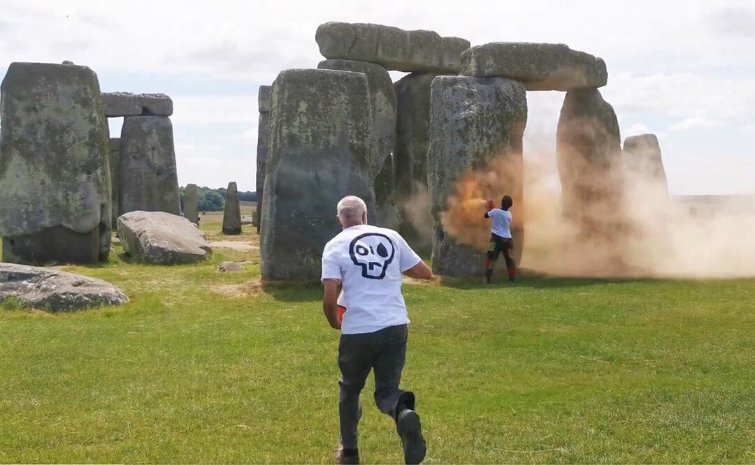 Dos hombres, activistas de Just Stop Oil, rociaron con polvo naranja los famosos monolitos de Stonehenge en Inglaterra. Foto. Tomada de video / @ST0NEHENGE