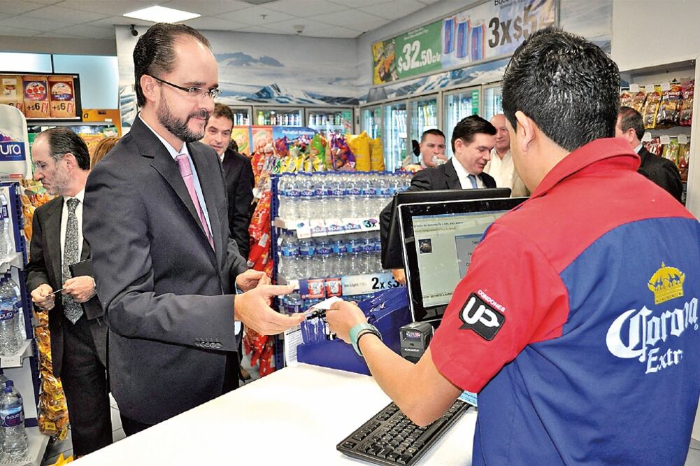 Carlos Ramírez Fuentes, presidente de la Consar, acompañado por el subsecretario de Hacienda, Fernando Aportela, entre otros funcionarios, realiza una aportación voluntaria a su Afore en una de las tiendas de la cadena Círculo K (CORTESÍA CONSAR)