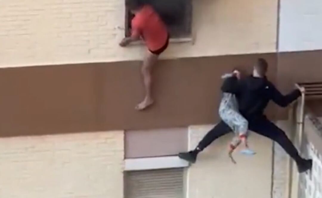 Un vecino trepa por una fachada para rescatar a una familia atrapada en un incendio. Foto: Tomada del video 