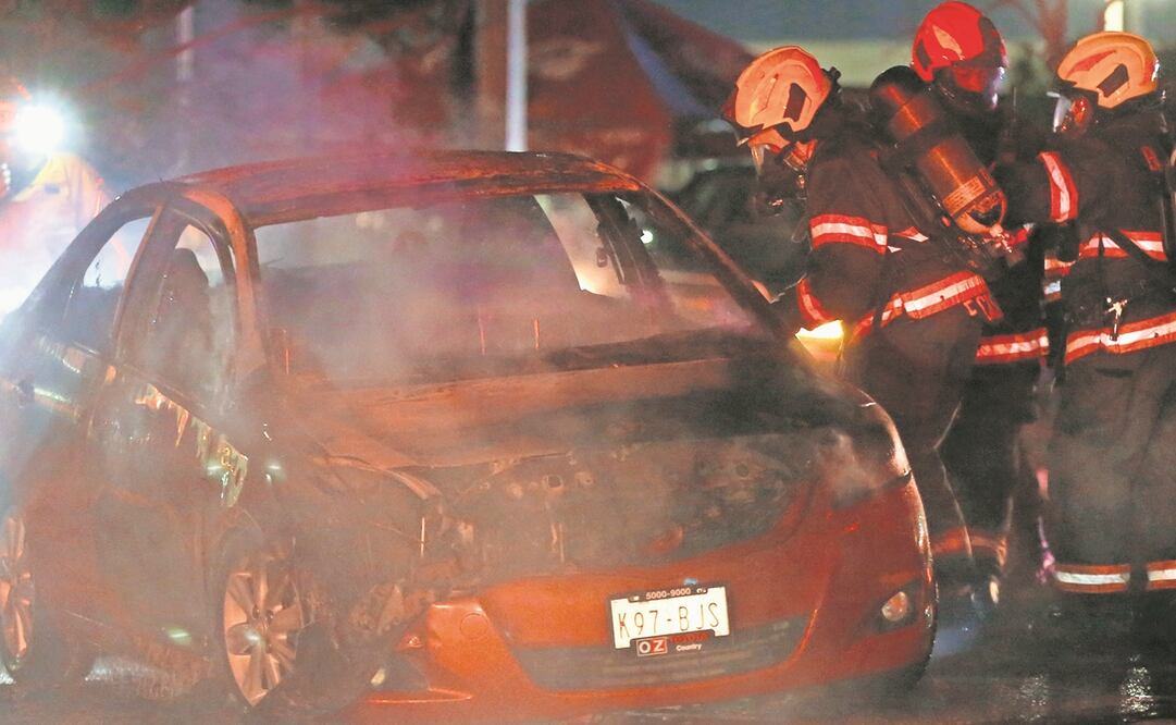 Bomberos tratan de sofocar el incendio de un auto en Zapopan, Jalisco, uno de los estados que esta semana atacó el crimen organizado.