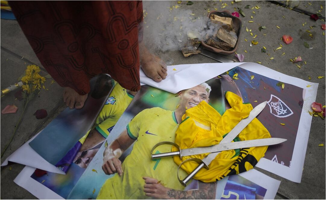 Un chamán peruano de pie sobre una foto del delantero brasileño Richarlison. FOTO: AP