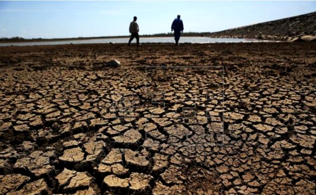 Dos obreros que caminan sobre la tierra agrietada del fondo de la presa "Sábanas Blancas", que se encuentra por debajo del mínimo de su capacidad de embalse en la provincia de Ciego de Ávila (Cuba). EFE/Archivo