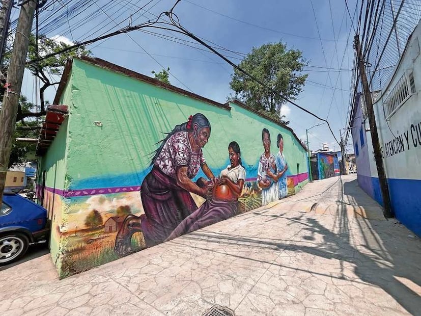 En el pueblo las fachadas lucen murales con escenas pensadas para los nuevos peatones, como este mural de una partera recibiendo a un bebé. Crédito: SONIA SIERRA