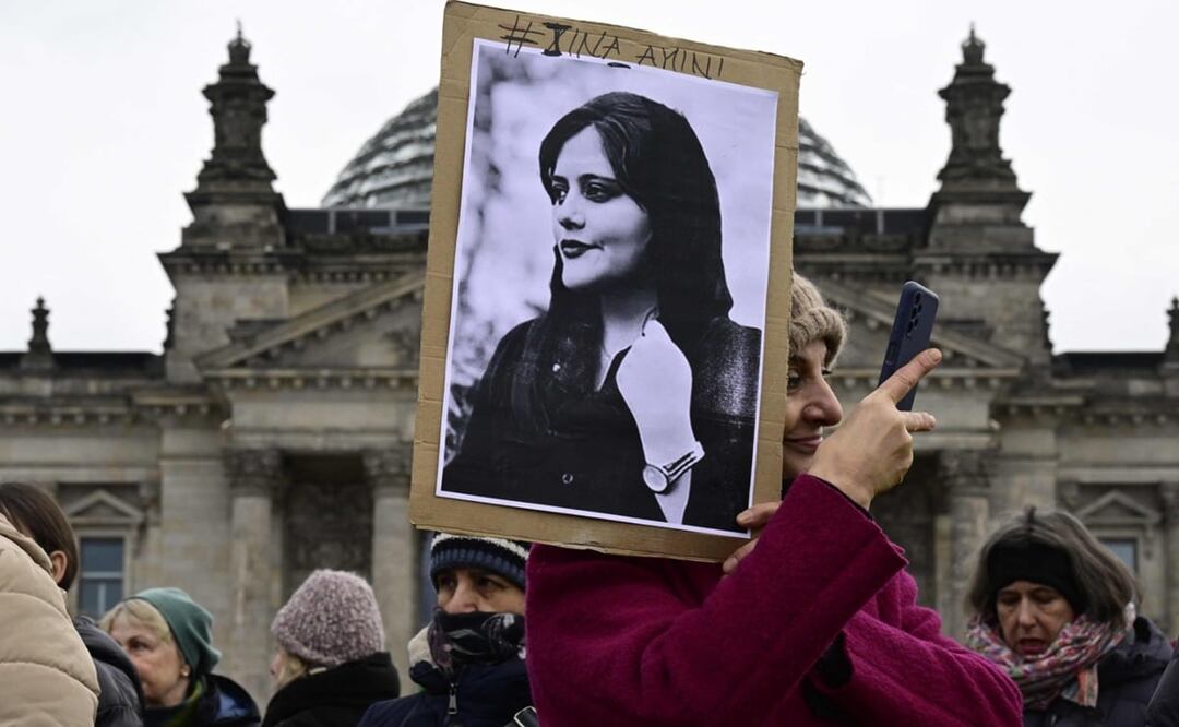 Una mujer se toma una selfie mientras sostiene un retrato de Mahsa Amini, una joven iraní que murió después de ser arrestada en Teherán por la policía de moralidad de la República Islámica. Foto: AFP