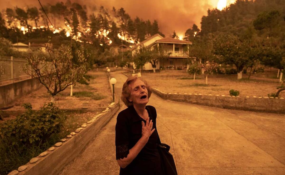 Panayiota Kritsiopi grita cuando el fuego se acerca a su casa en el pueblo de Gouves, en la isla de Eubea, Grecia, el 8 de agosto de 2021. Foto: "Incendio forestal en la isla de Eubea" © Konstantinos Tsakalidis, para Bloomberg News vía World Press Photo