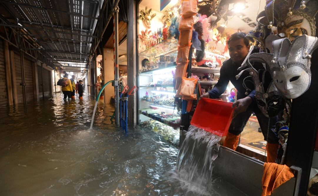Un tendero saca agua de su tienda en Venecia, Italia. Foto: EFE/Andrea Merola