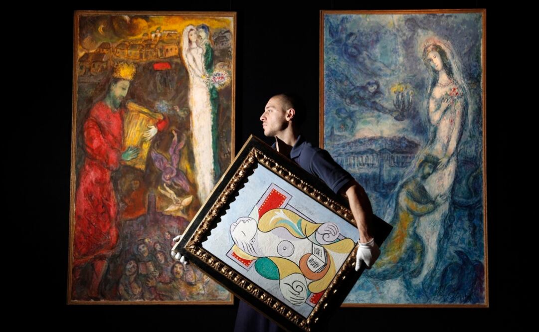 Un empleado de Sotheby's carga "La Lecture", de Pablo Picasso, cuando frente a dos obras de Marc Chagall's. Foto: Reuters / Luke MacGregor, archivo