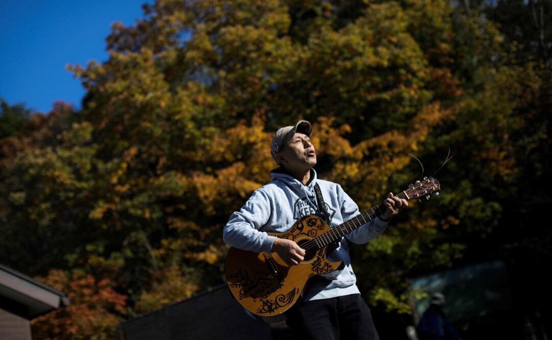El músico japonés Kyochi Watanabe toca su guitarra, a la entrada del bosque Aokigahara. Con su música, y su apoyo, busca evitar que la gente se quite la vida. Foto: AFP