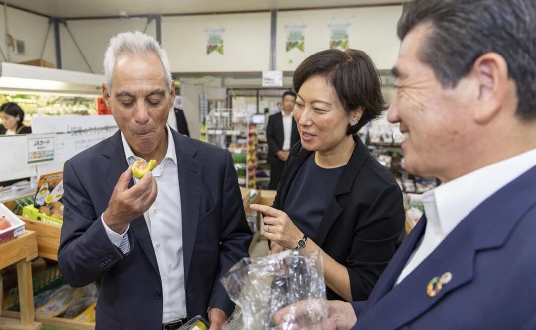 El embajador Eahm Emanuel, izquierda come un higo en el mercado de agricultores en la ciudad de Soma, prefectura de Fukushima. Foto: AP