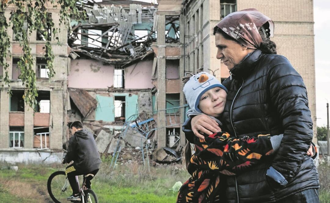 Olga Srednyakova, madre soltera de 51 años, abraza a su hija menor Vera, de ocho, mientras mientras otros cosechan hongos en un terreno abandonado de su escuela destruida en Konstantinovka, en la región de Donetsk. Foto: Yasuyoshi Chiba. AFP
