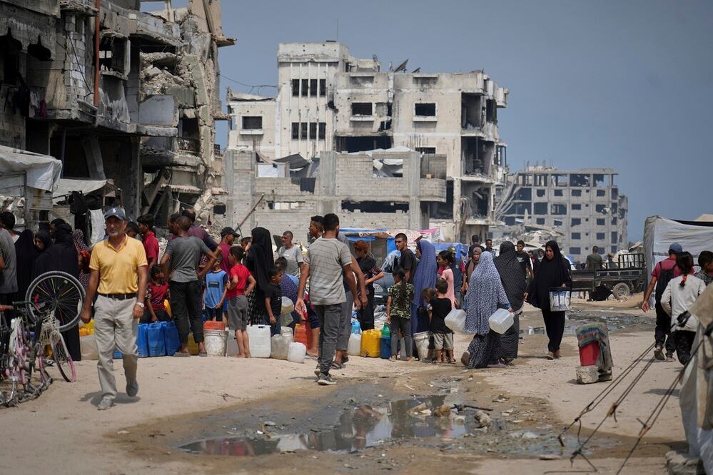 Palestinos se forman para recolectar agua en un punto de distribución en Ciudad de Gaza, donde el calor es extremo. FOTO: JEHAD ALSHRAFI. AP