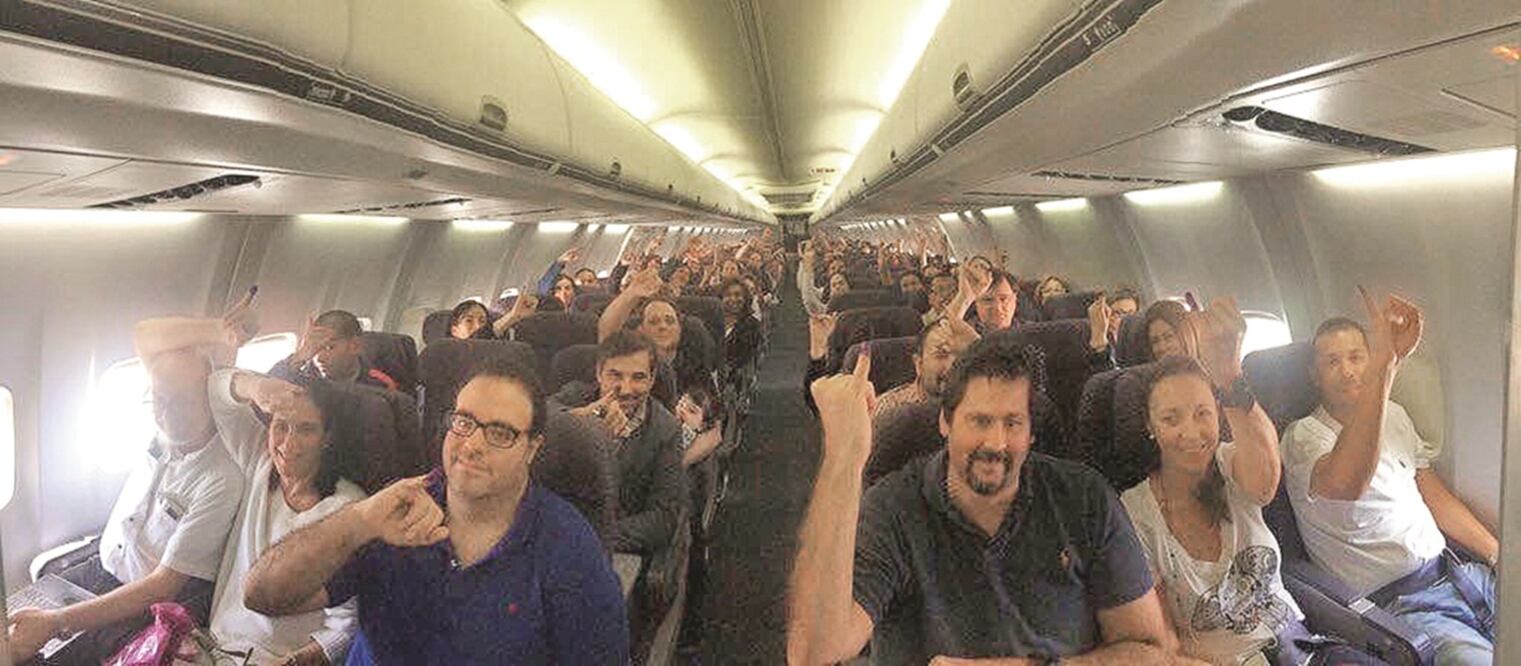 Pasajeros de un vuelo de Caracas a Nueva York en el que se encuentran venezolanos que viajaron a su país sólo para ejercer su sufragio. En la imagen muestran su dedo con la marca de que votaron (@ELNACIONALWEB)