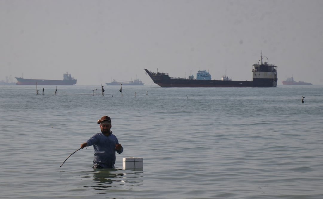 Un hombre se encuentra en el mar, aparentemente pescando, mientras buques de carga y de otro tipo pueden verse en el horizonte del estrecho de Ormuz, el lunes 27 de abril de 2026, frente a la costa de Bandar Abbas, Irán. Foto: AP