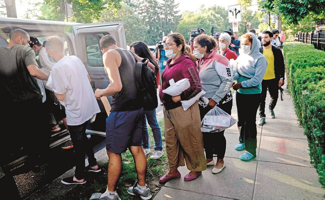 Migrantes de Venezuela, que abordaron un autobús en Texas, esperan ser transportados a una iglesia por voluntarios tras ser dejados frente a la residencia de la vicepresidenta Kamala Harris, en Washington. Foto: Stefani Reynolds/ AFP