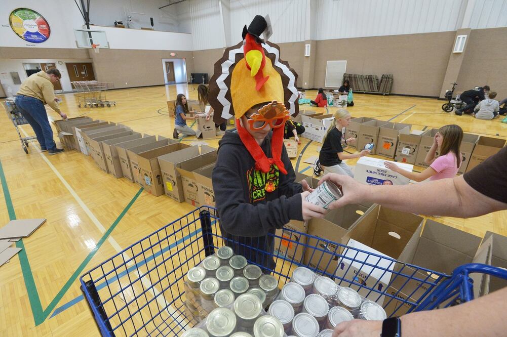 Nicky Benz-Bushling se une a los estudiantes de la escuela secundaria Lakeshore mientras preparan cajas para el Día de Acción de Gracias y organizan comidas festivas para los necesitados en Caring Cupboard, ubicado en la Iglesia Bautista Woodland Shores en Bridgman, Michigan. Foto: AP