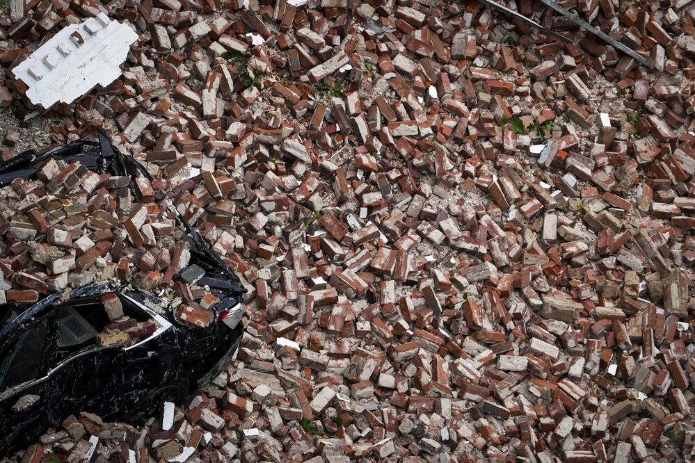 Un automóvil está cubierto de ladrillos después de que la pared de un edificio se derrumbara durante una tormenta en el centro de Houston. Foto: AP