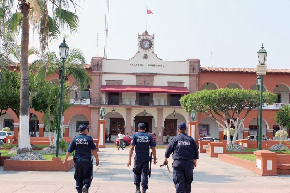 Tres elementos de la Policía Estatal en Apatzingán, Michoacán, rondan por el Palacio Municipal de esta localidad, donde la delincuencia organizada se ha disparado durante los últimos 10 años por la guerra contra el narcotráfico. Foto: ISAÍ MORALES