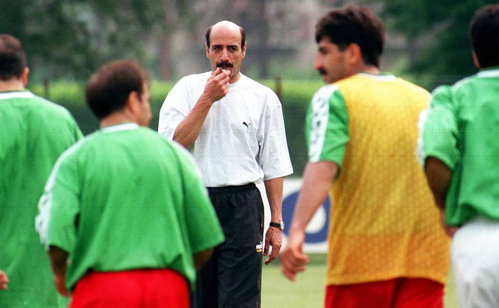 Selección iraní en 1998 con su entonces entrenador, Jalal Talebi. En 2022, el exentrenador de EU, Steve Sampson, confesó a la revista TIME que Talebi le contó cómo autoridades iraníes amedrentaron a los jugadores persas, retirando sus pasaportes y diciendo “si no le ganan a EU, no son bienvenidos a volver a Irán, ni sus familias podrán salir”; Talebi negó tal información. Foto: Luca Bruno/AP.