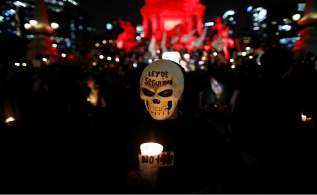 An activist in mask holds a candle during a protest against a new security bill, Law of Internal Security. The words on the mask read, "Law of security"- Photo: Edgard Garrido/REUTERS