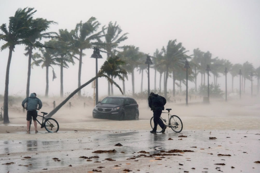 Dos hombres con sus bicicletas caminaron en calles inundadas de Fort Lauderdale, Florida, donde el huracán tocó tierra ayer (AP)