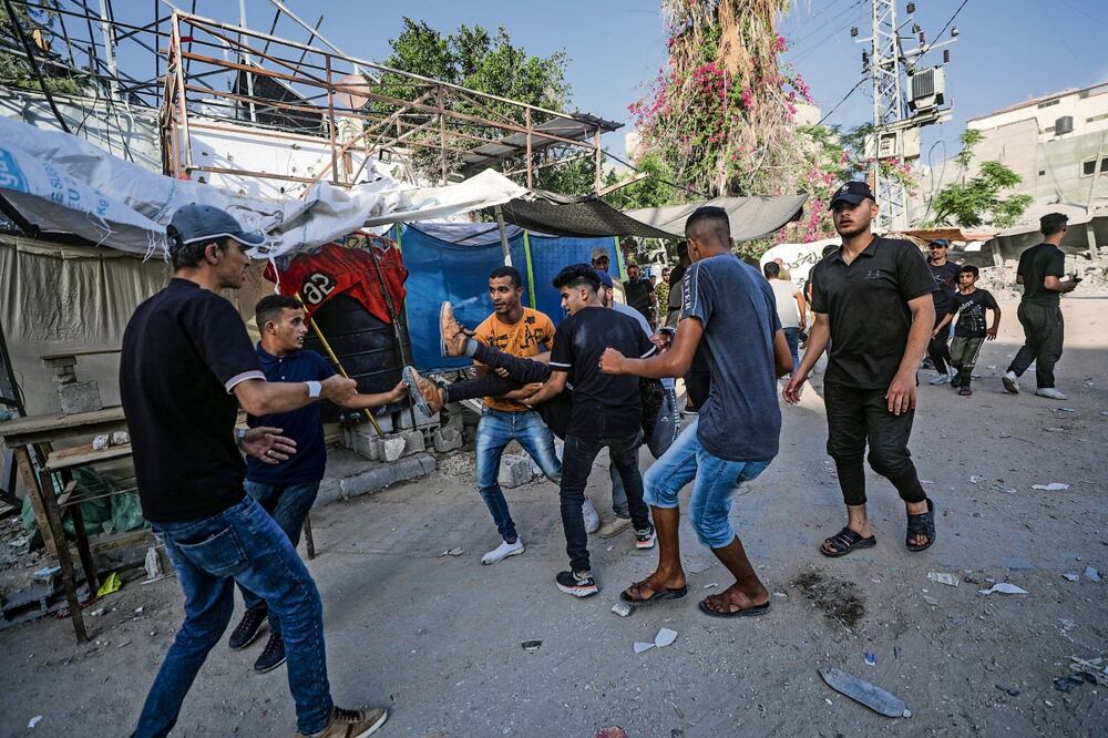 Palestinos cargan a un herido, tras un ataque israelí en el campo de refugiados Al Bureije, en el sur de Gaza Foto: EFE