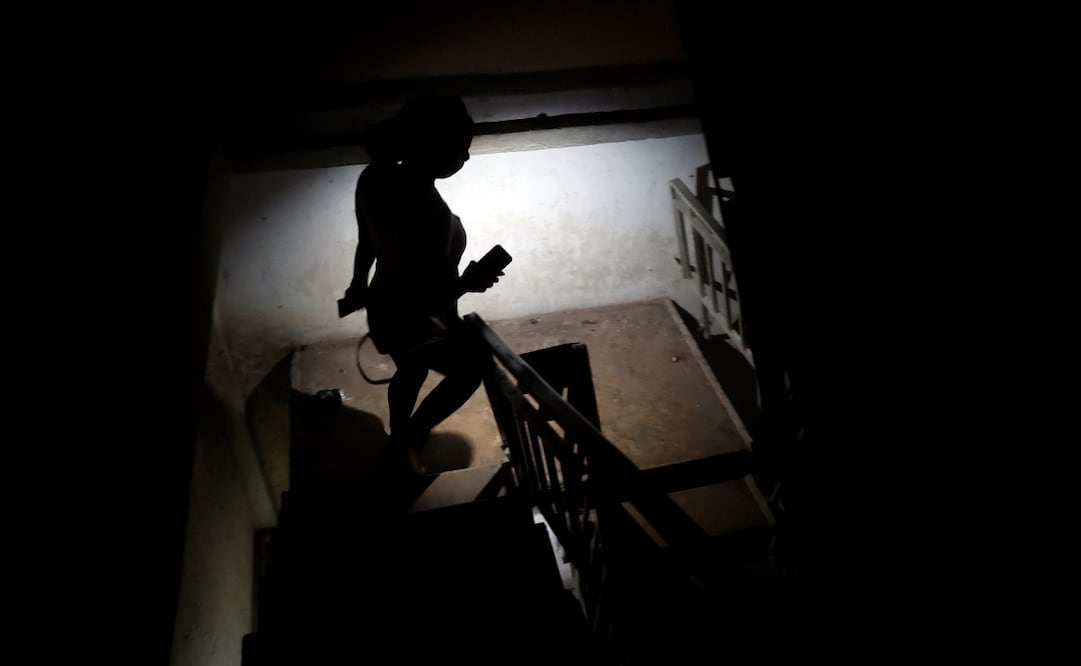 Una persona baja escaleras mientras alumbra con un teléfono este miércoles, en La Habana (Cuba). El asedio petrolero de EU ha agravado la ya crítica situación energética en Cuba, que desde el verano de 2024 sufre prolongados apagones diarios por todo el país por las frecuentes averías de sus obsoletas centrales termoeléctricas y la falta de divisas para importar crudo. Foto: EFE
