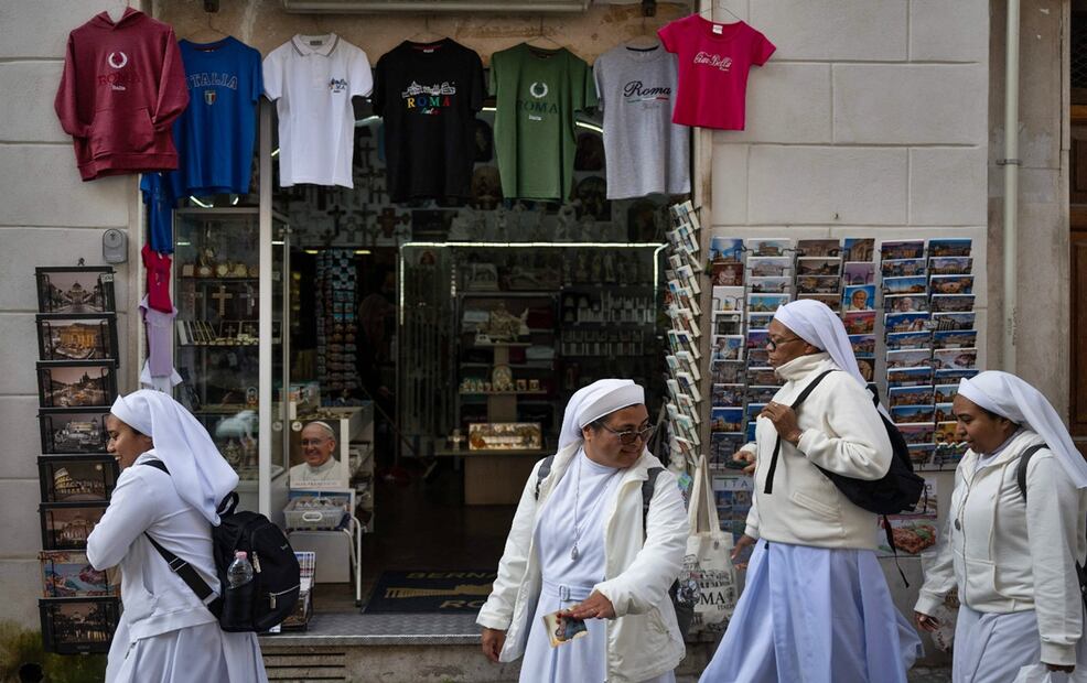 Religiosas caminan cerca de una tienda de recuerdos en las que se observan postales y recuerdos del papa Francisco en la calle Borgo Pio del Vaticano, en Roma, el 25 de abril de 2025.